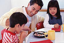 photo of a man and two children eating