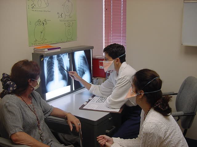 Masked doctors and patient discussing exam and patient xrays