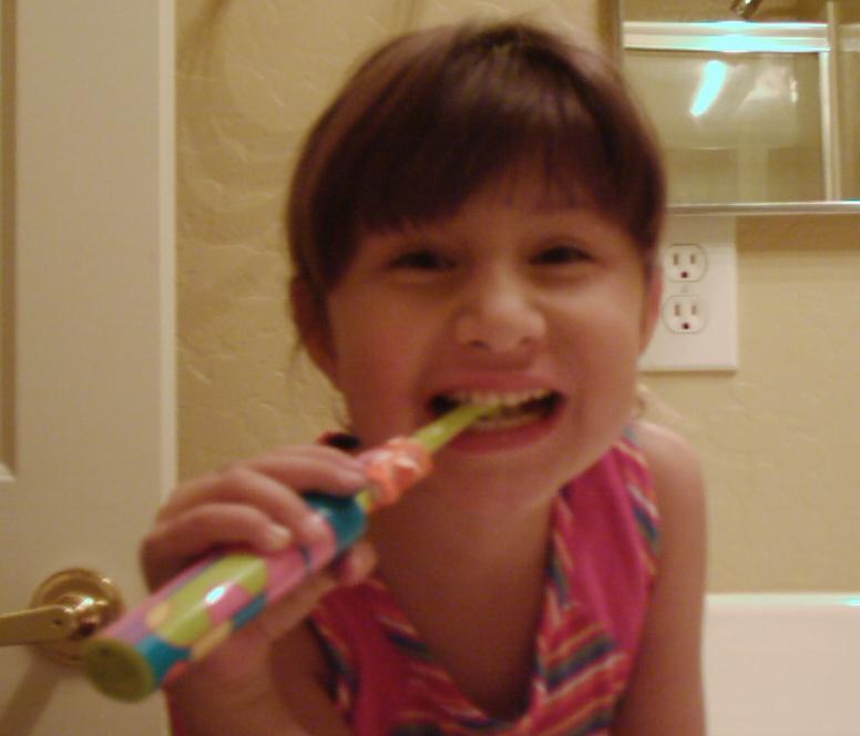 Isabelle G in Arizona brushing her teeth using her electric toothbrush - Age 5